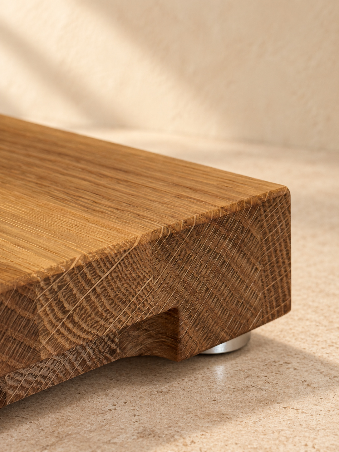 Detail eines massiven Holzbretts mit sichtbarer Maserung und eingefräster Griffmulde.